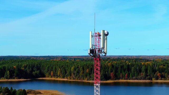Cellular antenna structure mounted on tower overlooking colorful autumn forest and lake