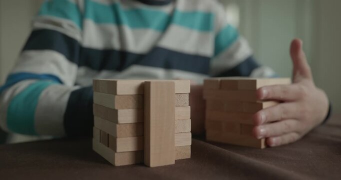 Close-up children's hands play with wooden bricks constructing structures. 4K 10-bit