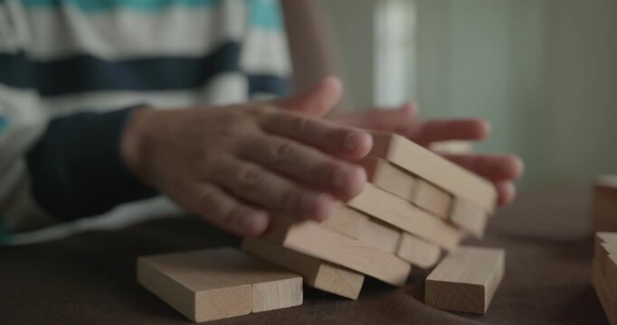 Close-up children's hands play with wooden bricks constructing structures. 4K 10-bit