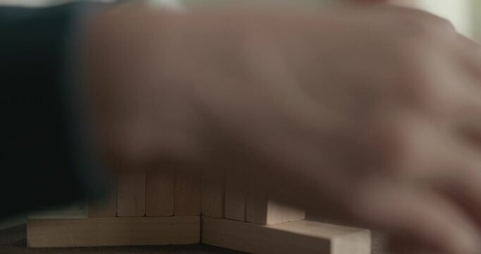 Close-up children's hands play with wooden bricks constructing structures. 4K 10-bit