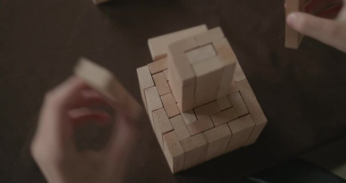 Close-up children's hands play with wooden bricks constructing structures. 4K 10-bit