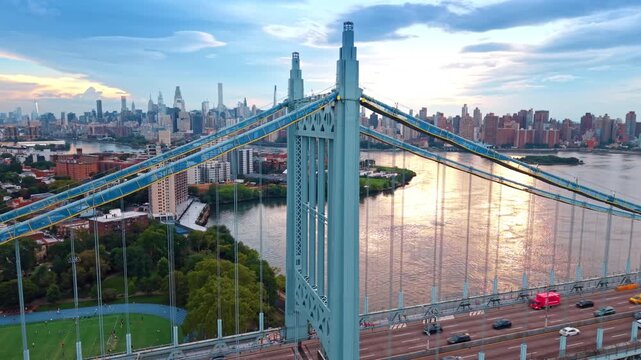 Distancing from the blue metal support of the Robert F. Kennedy Bridge. The East River surface reflects the setting sun. New York City skyline in the backdrop.