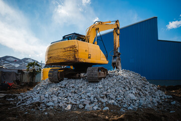 A powerful yellow excavator at a construction site, seen from a low angle, ready for demolition work. © garcon daily photo