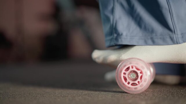 Close up shows woman feet in socks rolling over pink wheels. Foot movement is captured as woman walks indoors on carpeted floor with blue clothing roller