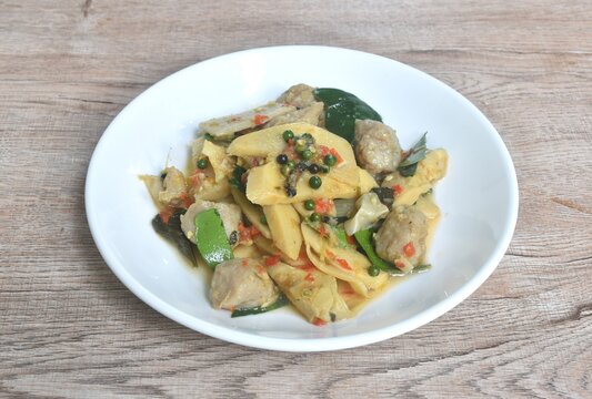 spicy stir fried bamboo shoot and clown featherback fish ball with curry couple basil topping peper on plate