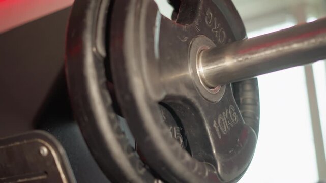 Close up focus remains steady throughout. heavy metal dumbbell with black rubber coated weight plates marked 10KG is shown in detail highlighting industrial texture and engraved text on each