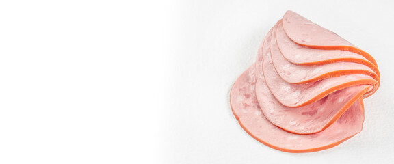 Folded slices of pink processed meat with orange edges arranged on a white surface, leaving open space beside the food, isolated food composition © Надія Коваль