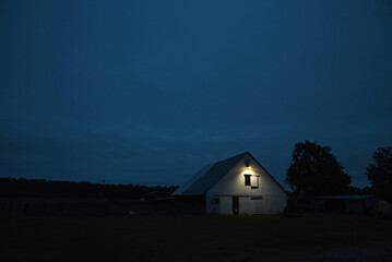 A century old barn is illuminated by a solitary light just before dawn. © D Guest Smith