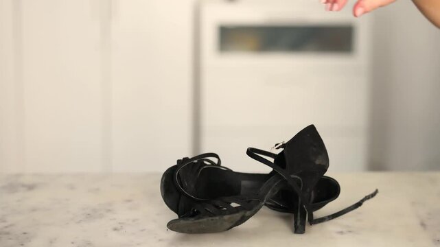 Close view of black satin dance pumps resting on a marble tabletop