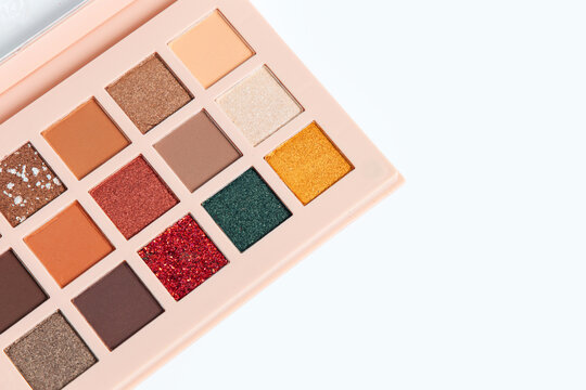 Cosmetic makeup palette with various eyeshadow colors placed on a plain white background