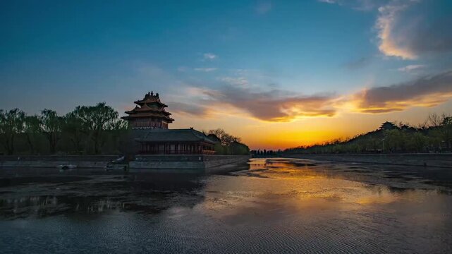 Traditional Chinese pavilion at Beijing Forbidden City moat during golden hour sunset with calm water reflections