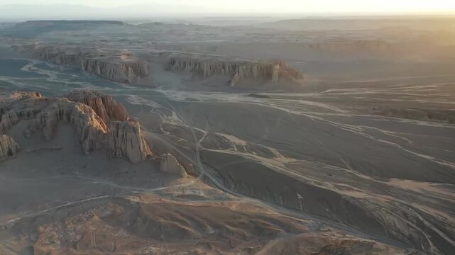 Aerial drone view of the Da Hai Dao ancient Silk Road trail in Xinjiang desert at golden hour, showcasing eroded yardang landforms and arid basin terrain