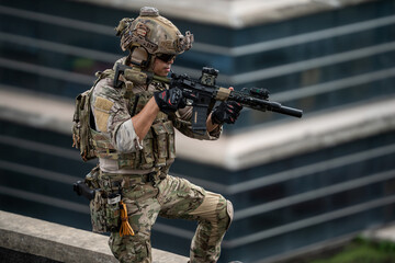 Fototapeta premium A tactical operator stands alert on a rooftop holding a rifle during an urban security operation, conveying intense focus, determination, and tactical readiness in an outdoor environment.