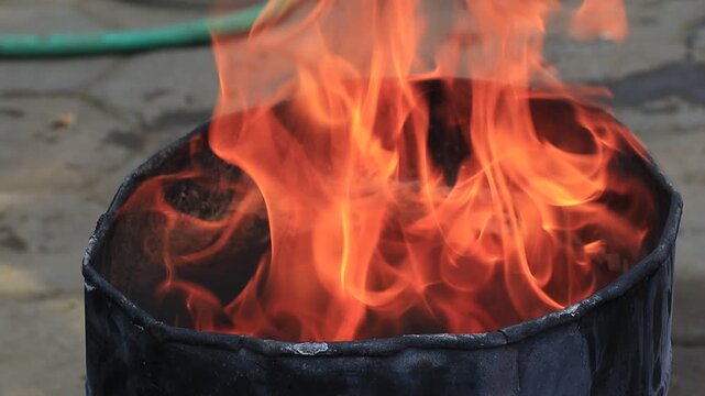 A person safely smothers flames in a metal container by covering it with a thick woven fire blanket, demonstrating a clear fire extinguishing technique for emergency response and fire safety too.
