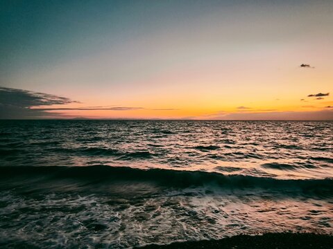 &bull;  Horizontal twilight layers background with beautiful sunset over calm sea waves white foam on beach scenic orange gradient sky ocean horizon nature.