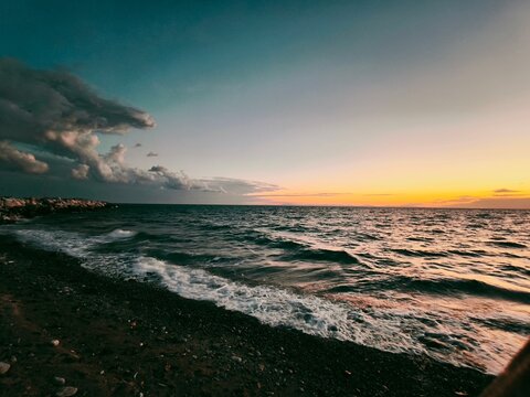 Dramatic stormy clouds over calm sea waves background beautiful sunset gradient sky with orange color over ocean horizon scenic twilight dusk nature.