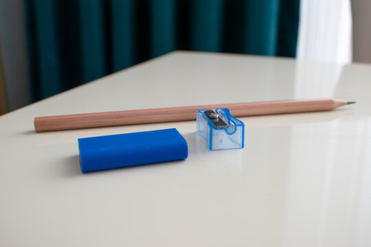 Blue eraser and transparent pencil sharpener with wooden pencils on white desk