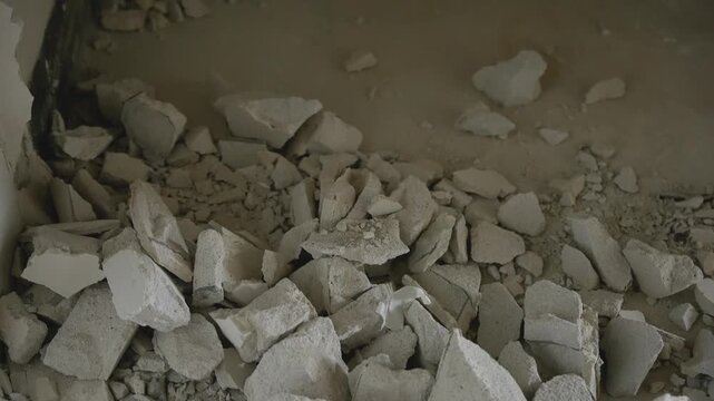 Close up of broken plaster and concrete debris on a dusty floor during demolition