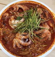Spicy Korean braised octopus and seafood stew with water parsley and sesame seeds in a round dish © tommy