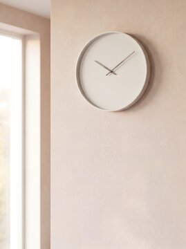 Minimalist white wall clock hanging on a textured beige wall in a bright room