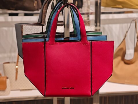 Shanghai, China-Jan.13th 2026: colorful Michael Kors Pratt small leather tote bags on display shelf.