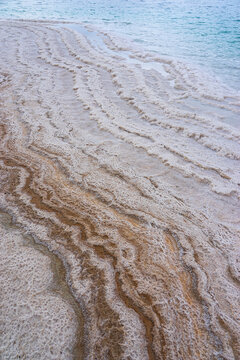 Natural salt crystal formations along turquoise water at a saline shoreline, Dead sea