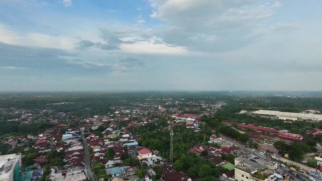 Aerial view of a sprawling small town featuring dense residential houses and buildings under a bright daytime sky with clouds. Urban landscape, community, and travel concept.