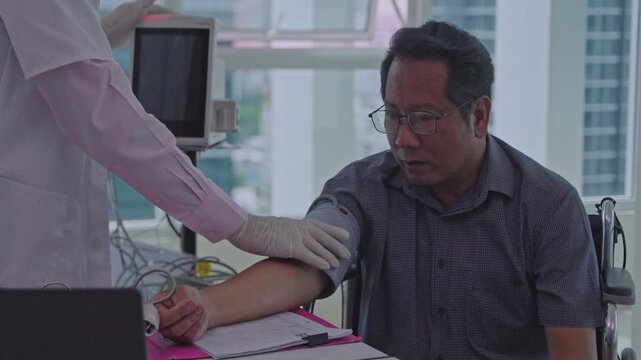 Doctor examining adult man wheelchair during blood pressure medical consultation, patient receiving clinical examination modern hospital clinic while nurse records routine healthcare information