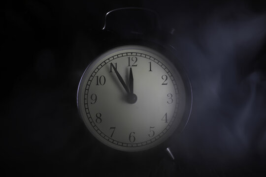 Vintage Analog Alarm Clock in Dim Light with Smoke, Emphasizing Time and Mystery