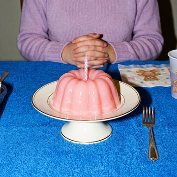 Minimal Retro Style Birthday Pink Gelatin Mold Dessert With Burning Candle Served On Stand Table
