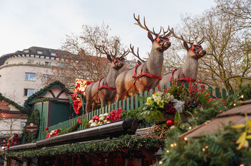 Festive reindeer figures decorate a Christmas market stall beneath winter trees in Cologne, Germany © Aleksandr Fedosov