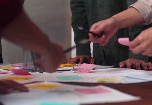 Top-down view of a team brainstorming with colorful sticky notes on a table during a creative workshop.