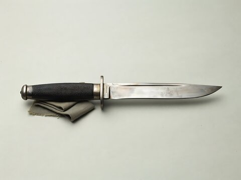 Vintage military combat knife with black checkered grip and steel blade