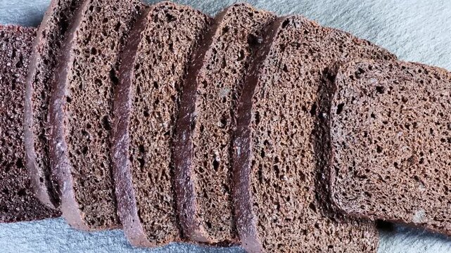 Sliced brown bread on black flat slate plate, close-up