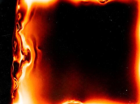 Film burn light leak overlay with fiery orange flames burning vintage frame edges on black background, retro analog transition effect