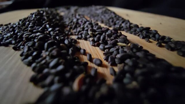 Close-up macro video of organic black basil seeds neatly arranged in parallel lines on a textured wooden board. Perfect for healthy food and culinary projects.   