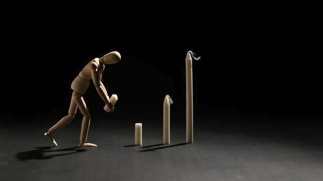 Wooden mannequin arranging or pulling down a candle bar graph, representing financial risk, stock market crash, economic downturn, and business loss.