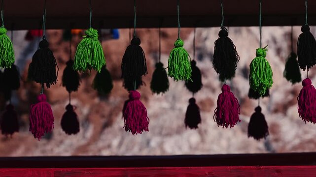 Colorful decorative yarn tassels hanging and gently swaying, traditional oriental tribal handmade hanging ornaments, Traditional Persian decoration used in transportation and interior design.