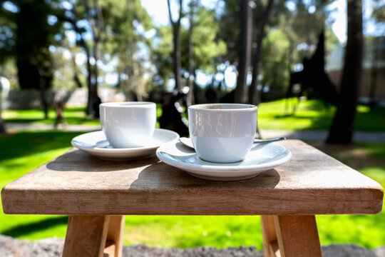 Two Cups of Espresso Coffee on a Wooden Table in a Sunny Park. Concept of relaxation and taking a peaceful break.