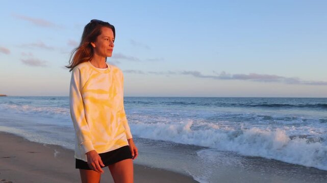 Woman walking along the beach at sunset. Santa Monica California.