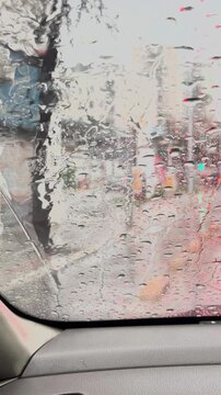 Heavy rain on vehicle window in urban area
