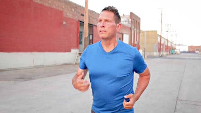 Middle-aged man, working on getting back into shape, jogging through the warehouse district in Los Angeles.
