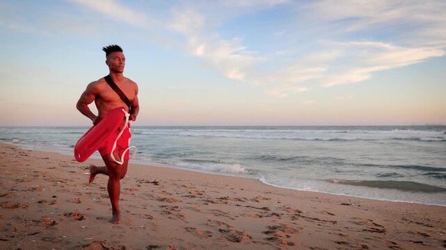 African American lifeguard running along the beach in Southern California at Sunset. Lifeguard's left hand is disabled.