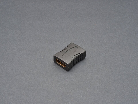 Black HDMI Adapter Connector - A close-up studio shot of a black HDMI adapter or connector with gold-plated contacts on a neutral gray background, highlighting its technic