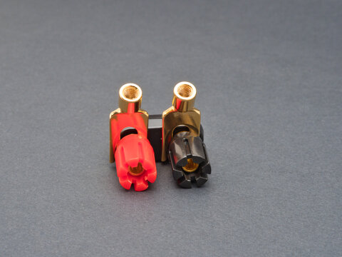Gold Plated Banana Plug Binding Posts - Two gold-plated banana plug binding posts, one with a red insulator and the other with a black insulator, on a dark gray background.