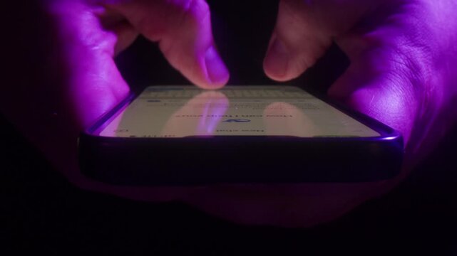 AI chat bot on phone, close up of hands typing prompt on smartphone screen in neon purple light, person using artificial intelligence assistant app at night