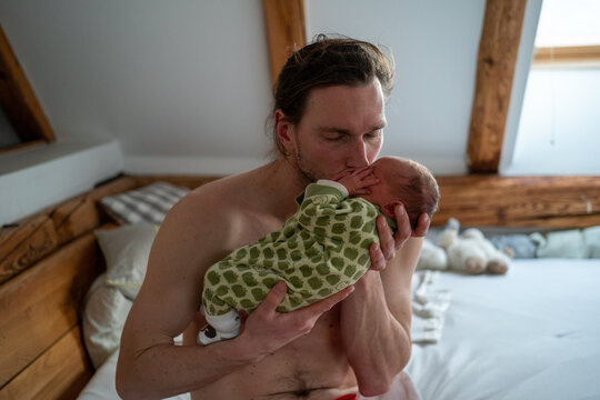 A loving dad kissing his tiny newborn baby girl