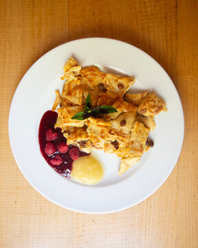 Traditional Austrian Kaiserschmarrn served with fresh raspberries and sweet apple sauce on plate
