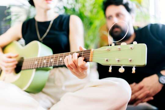 Couple enjoying creative hobby playing acoustic guitar