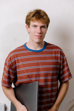 Cheerful creative man holding a laptop, posing with confidence.